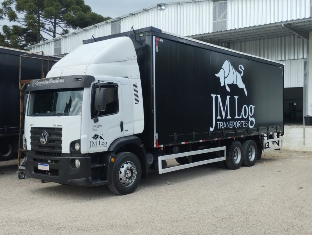 Foto de um caminhão com lona preta da JM LOG.